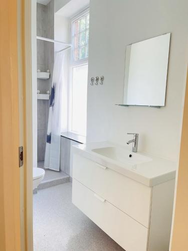 a white bathroom with a sink and a mirror at aday - Aalborg mansion - Open bright apartment with garden in Aalborg
