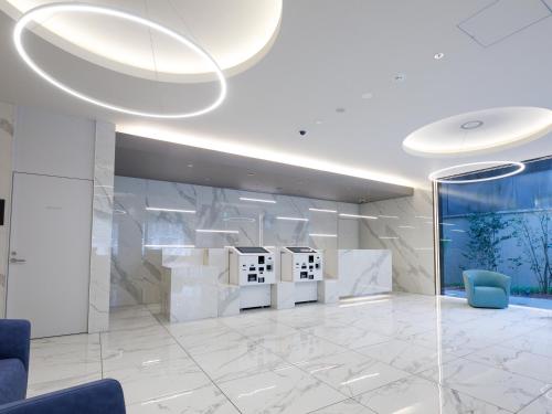 an office lobby with white marble walls and blue chairs at Fukuoka U-BELL Hotel in Fukuoka