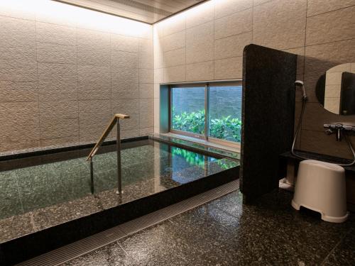 a bathroom with a swimming pool and a window at Fukuoka U-BELL Hotel in Fukuoka