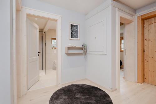 a hallway with white walls and a door and a rug at mei chalet - DAS BARBARA in Leutasch
