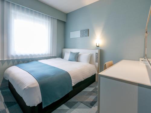 a blue bedroom with two beds and a window at Fukuoka U-BELL Hotel in Fukuoka