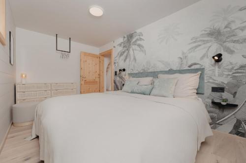 a bedroom with a large white bed and palm trees wallpaper at mei chalet - DAS BARBARA in Leutasch