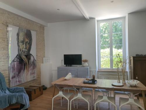 a living room with a table and a painting of a man at Maison Laurenza La grande suite 1760 in Saint-Jean-de-Liversay