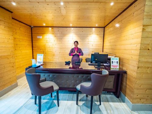 a woman standing behind a counter in a wooden room with chairs at Sumitel Shangrila in Tādong
