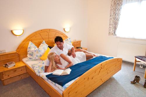 a man and woman laying on a bed reading at Appartements Hartlbauer in Dorfgastein