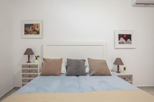 a white bedroom with a blue bed with two lamps at Eleni's Studio in Heraklio Town