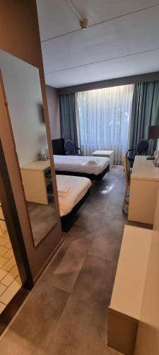 a hotel room with two beds and a mirror at City Hotel Winschoten in Winschoten
