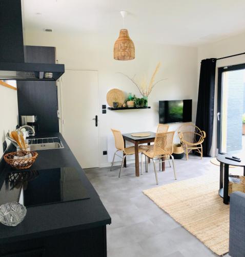a kitchen and living room with a table and chairs at Appartement Beau Séjour - Accès Piscine in Criel-sur-Mer