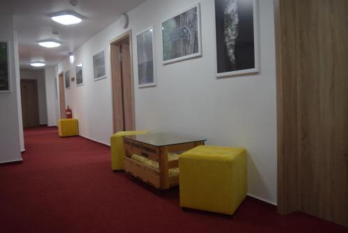 a hallway with a table and two yellow stools at HOTEL BIKE & HIKE in Obersuhl