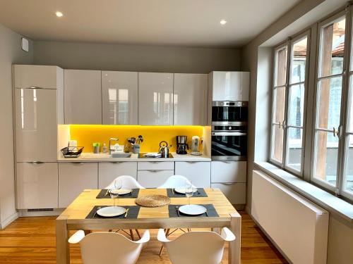 cocina con mesa de madera y armarios blancos en Appartement Hyper-centre Colmar en Colmar