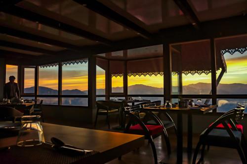 a restaurant with tables and chairs with the sunset in the background at Sumitel Vista 800m from Mall Road in Darjeeling