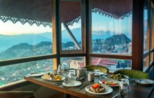 a table with plates of food on it in front of a window at Sumitel Vista 800m from Mall Road in Darjeeling