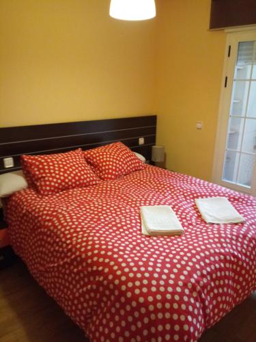 a bedroom with a red bed with two towels on it at Ávila Flats Pz Ejército Avila in Ávila