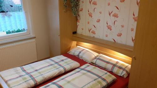 a bedroom with a bed with pillows and a window at Grosszügige Wohnung für 4 Personen in Ostfriesland mit E- Ladesäule in Utarp