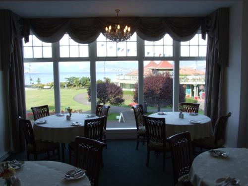a dining room with two tables and a large window at The Victoria Hotel in Rothesay
