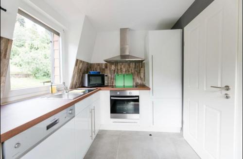 eine Küche mit weißen Schränken, einem Waschbecken und einem Fenster in der Unterkunft Rapunzel in Neuenbürg