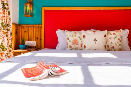 a bed with a red headboard and two slippers on it at Zen Manali by Keekoo Stays in Manāli