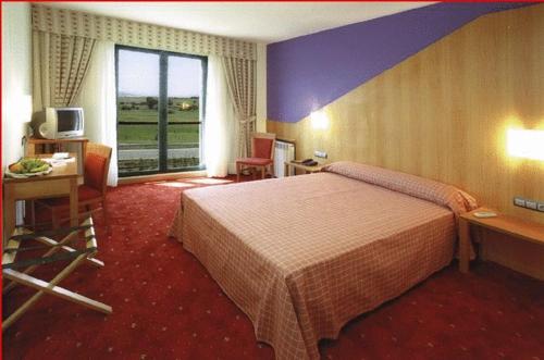 Habitación de hotel con cama, escritorio y ventana en Hotel Mirador de Gornazo, en Gormazo