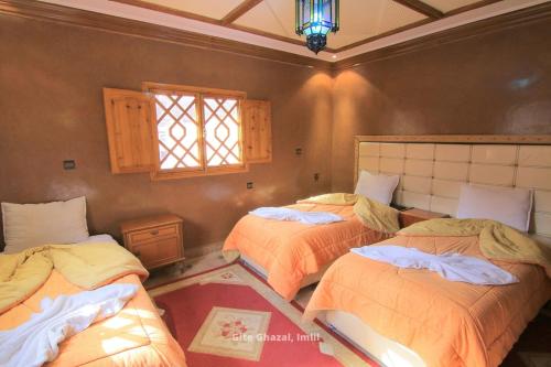 a bedroom with three beds and a window at Gite Ghazal - Atlas Mountains Hotel in Imlil