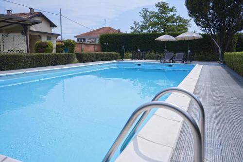 a large blue swimming pool with chairs and umbrellas at Locanda OSTERIA LA MILONGA in Agliano Terme