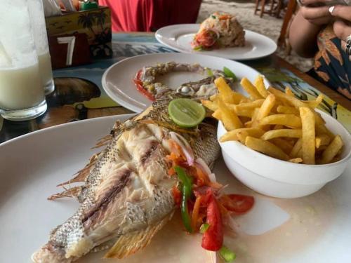 a plate of food with a fish and french fries at Mocco Beach Villa in Kendwa