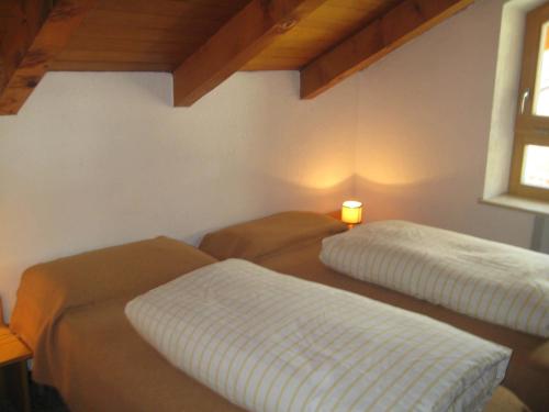 two beds in a room with a light on the wall at Appartamenti Decrestina in Campitello di Fassa