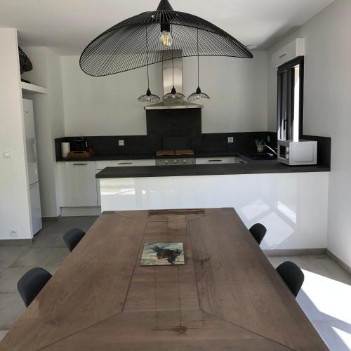 une cuisine avec une table en bois, des chaises et un grand éclairage dans l'établissement Villa l'art de fer, à Saint-Paul-de-Vence