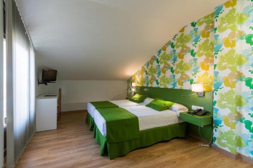 1 dormitorio con 1 cama con colcha verde y blanca en Hotel Bemon Playa en Somo
