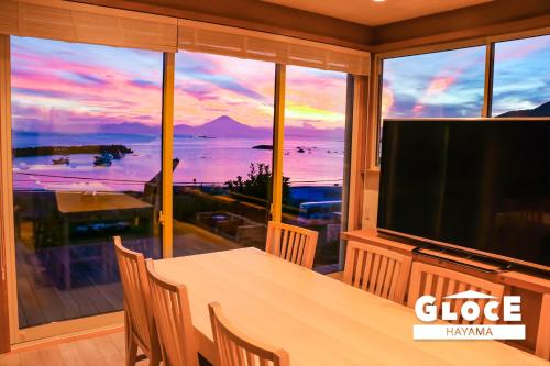 a dining room with a table and a large screen television at GLOCE 葉山 Ocean View House 都心から1時間 湘南の絶景を独り占めペットok 出張BBQ有り in Yokosuka