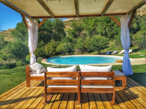 una terraza de madera con sillas y una piscina en Masía el Cabrero en Villarroya de los Pinares