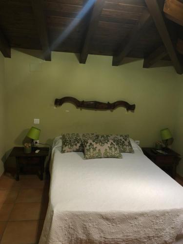 1 dormitorio con 1 cama blanca y 2 mesas con lámparas en Hostal La Caballeriza, en Malpartida de Cáceres