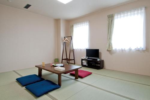 a living room with a table and a tv at Hotel New Ohte in Hakodate