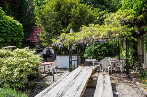 a wooden bench in a garden with a table and chairs at Hotel Sonne Interlaken-Matten in Interlaken
