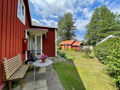 una casa roja con un banco y una mesa en el patio en Skruvshultkvarn, en Berga