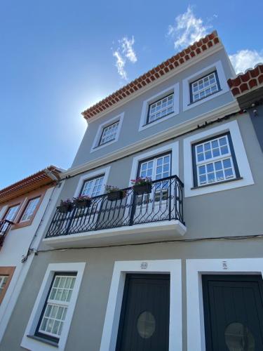 a white building with a balcony and a blue sky at Casas do Mercado - Casa Nautilo in Angra do Heroísmo