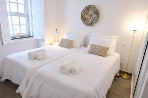 two beds with white sheets and towels on them at Casas do Mercado - Casa Nautilo in Angra do Heroísmo