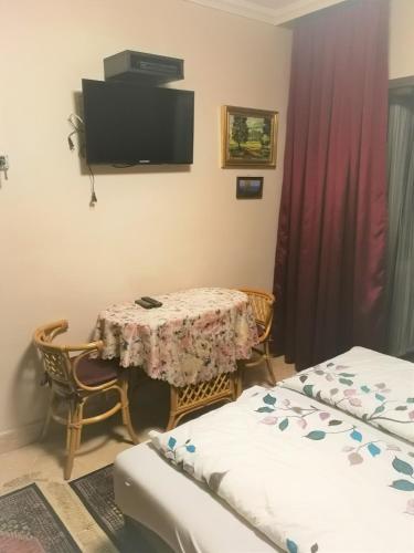 a room with a table and a tv on the wall at Big Apartman in Hajdúszoboszló