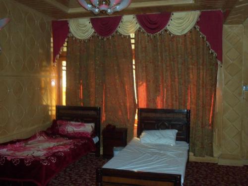a bedroom with two beds and a window with curtains at Manila Huts in Naran