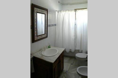 a bathroom with a sink and a toilet and a mirror at Casa El Carmen in Ciudad Real