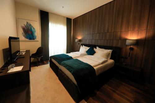 a bedroom with a bed and a desk and a window at Premium Park Hotel in Prizren