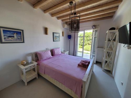a bedroom with a bed with pink sheets and a window at Villa Elena in Ornos