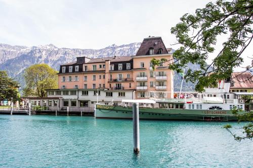 a large building in the middle of a lake with a boat at Hotel Du Lac in Interlaken