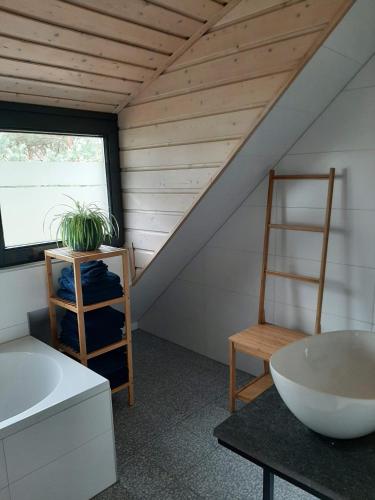 a bathroom with a white sink and a chair at Vakantiehuis met hottub en barrelsauna in Ommen
