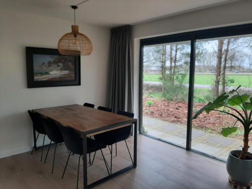 a dining room with a table and chairs and a sliding glass door at Vakantiehuis met hottub en barrelsauna in Ommen