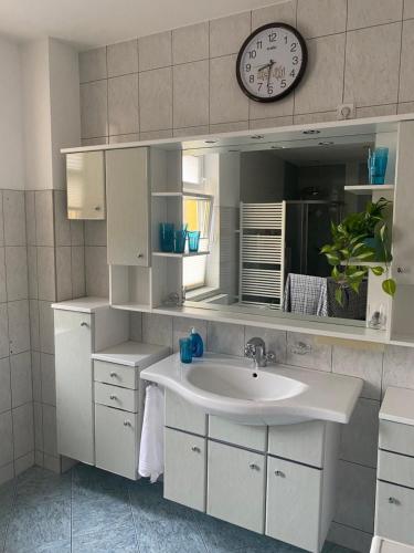 ein Badezimmer mit einem Waschbecken und einer Uhr an der Wand in der Unterkunft Ferienwohnung mit Terrasse in Aue
