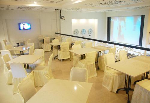 a room with tables and white chairs and a screen at Gandhi Inn in Medan