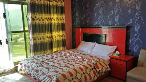 Bett mit rotem Kopfteil in einem Schlafzimmer in der Unterkunft Fridays Hotel in Shongran