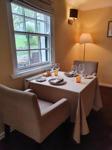 a table with a white table cloth and chairs and a window at Ardeonaig Hotel & Restaurant in Ardeonaig