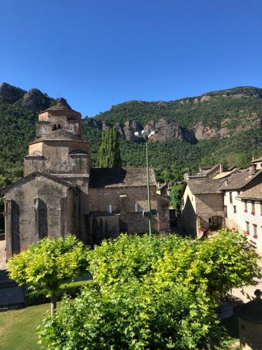 an old building in a village with mountains in the background at apartamentos turisticos san juan de la peña in Santa Cruz de la Serós