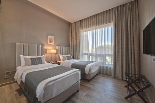 a hotel room with two beds and a window at The House Boutique Suites in Amman